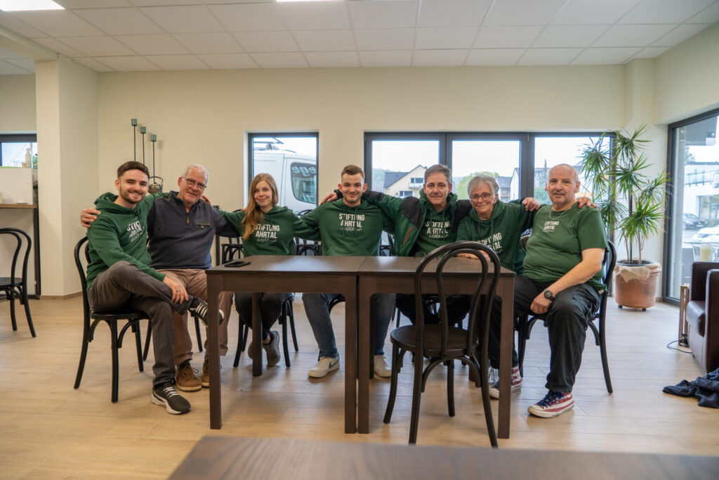 Ehrenamtliche der Stiftung Ahrtal sitzen zusammen Arm in Arm nach dem Aufbau des Veedelstreffs in Hemessen. EIne typische Förderung von Vereinen und Initiativen.