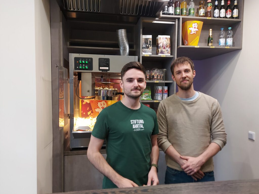 Nick Falkner (links/ Gründer und ehrenamtlicher Geschäftsführer der Stiftung Ahrtal) und Jurij Stroeve (rechts/ Inhaber des Kino-Center Rhein-Ahr) stehen an der Verkaufstheke des Kino-Center Rhein-Ahr